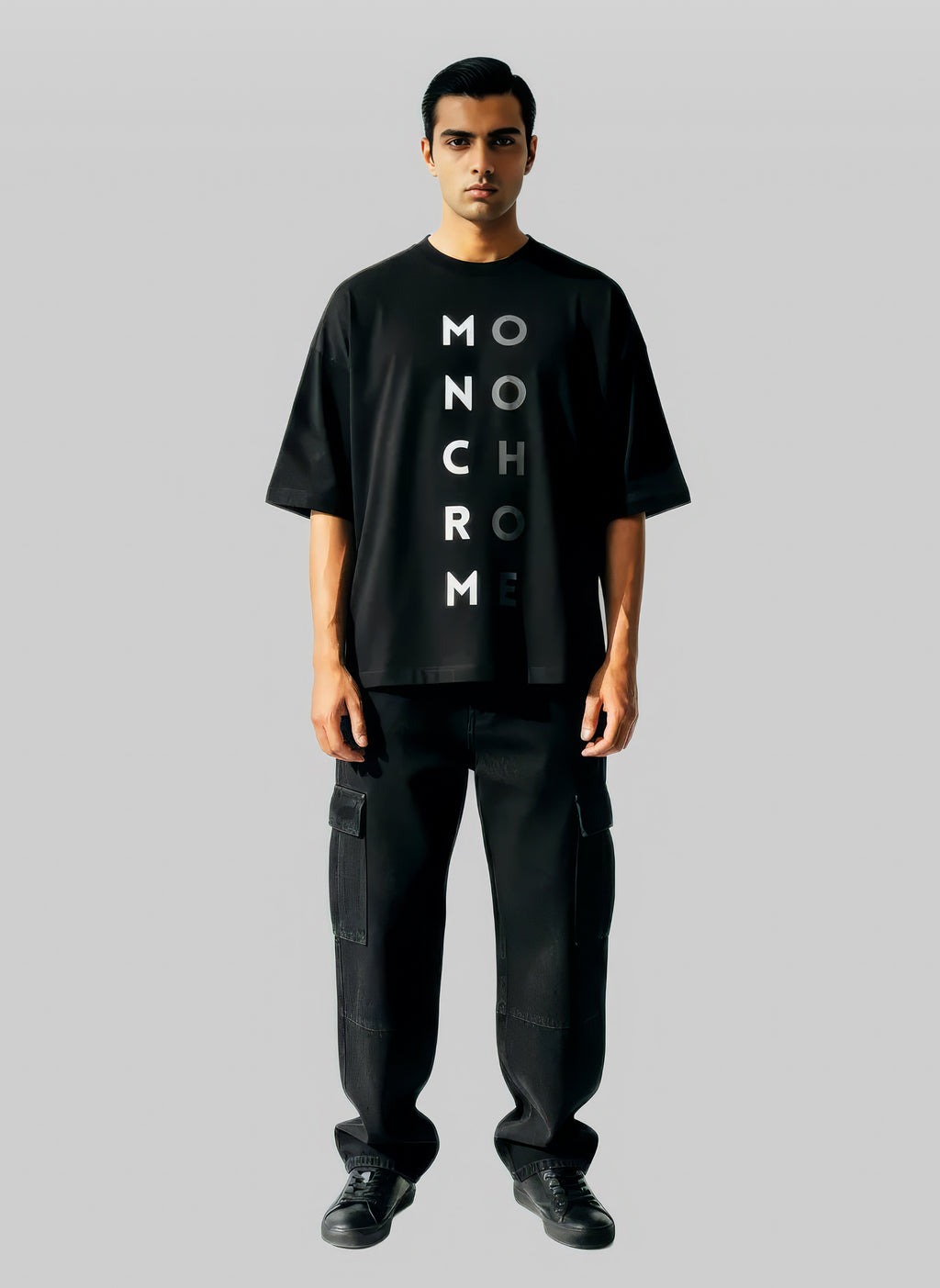 Man wearing a black t-shirt with 'MONOCHROME' text on a gray background