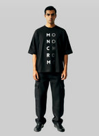 Man wearing a black t-shirt with 'MONOCHROME' text on a gray background