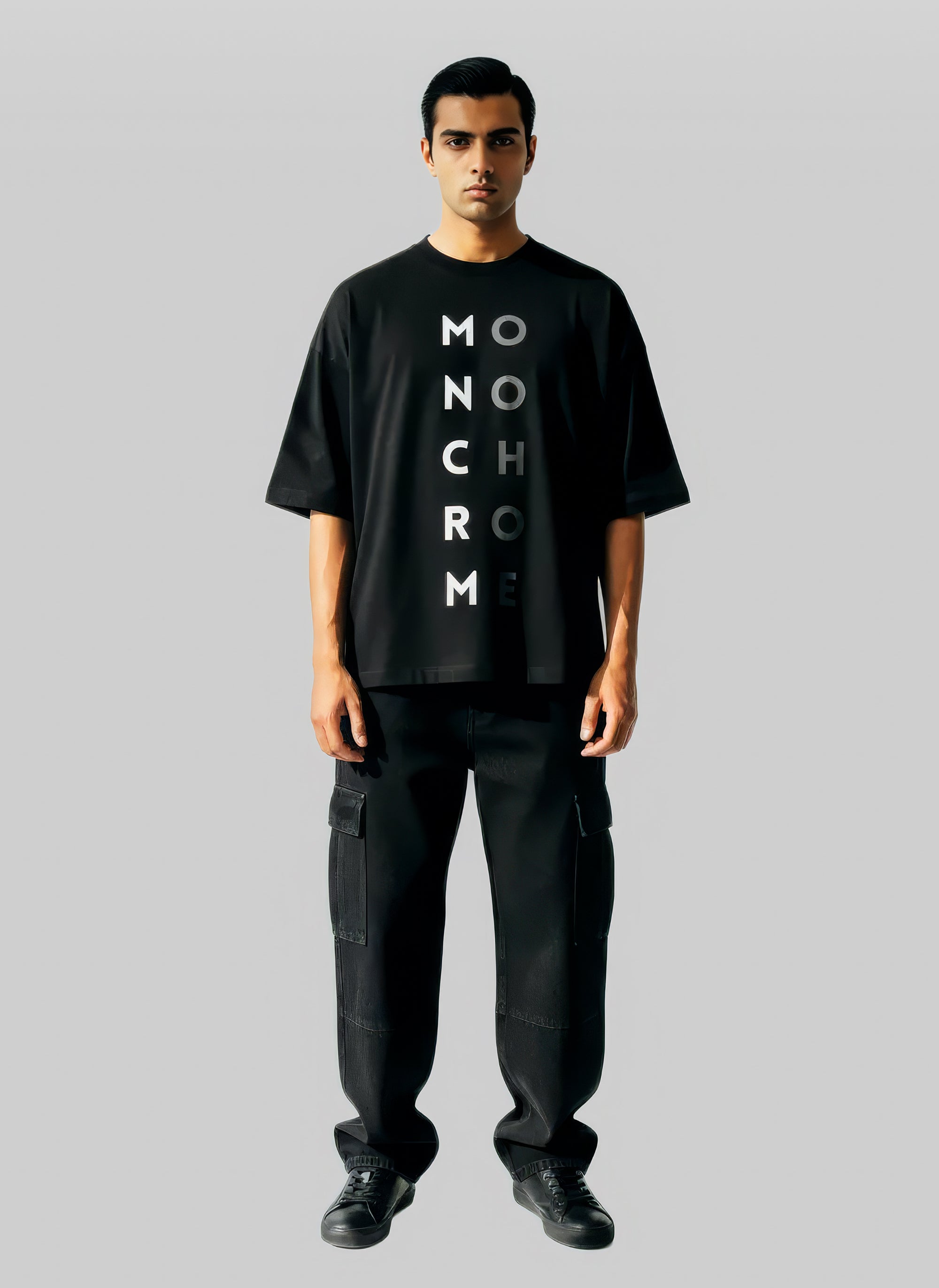 Man wearing a black t-shirt with 'MONOCHROME' text on a gray background