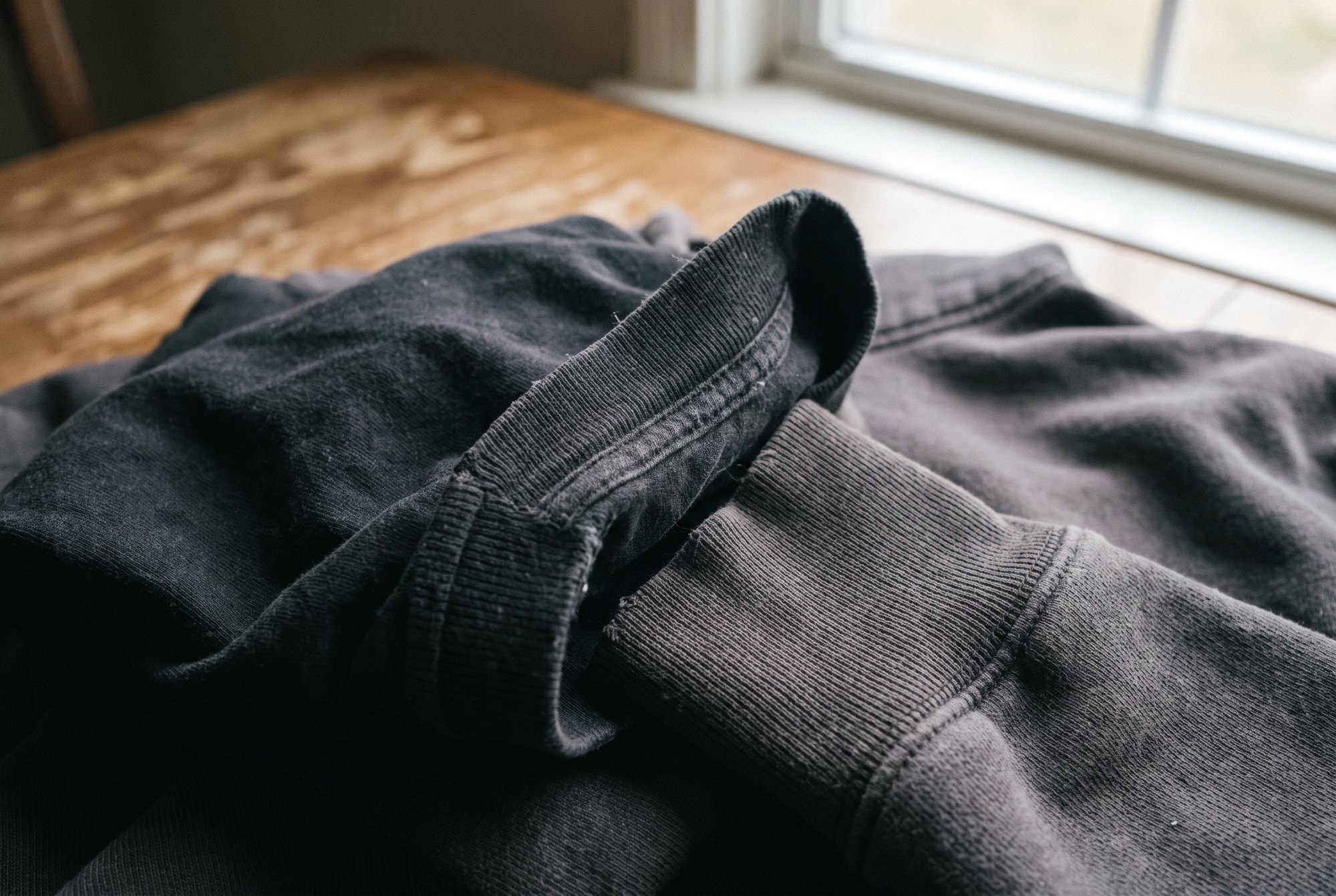 Extreme close-up of a ribbed cotton collar and cuff on a black tee and hoodie