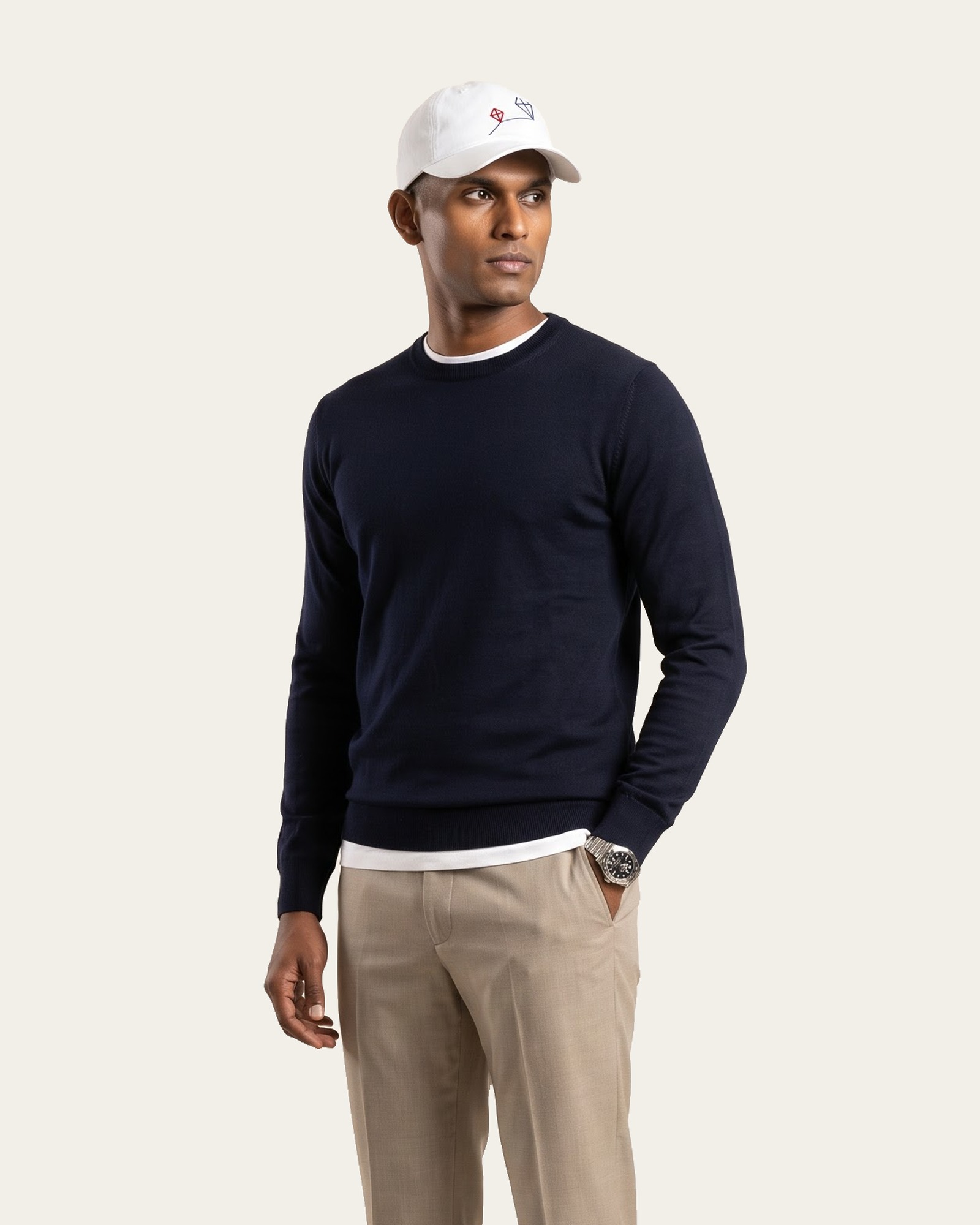 PATANG cap in Rui White with embroidered kites, worn with a dark sweater and light trousers